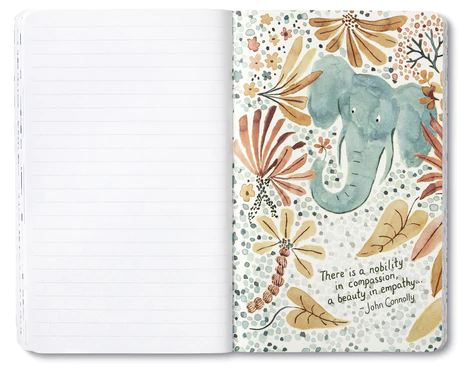 The "Every Kindness Matters" journal by Compendium showcases a watercolor illustration of an elephant encircled by flowers and leaves. A quote elegantly displayed in typography states, "There is a nobility in compassion, a beauty in empathy." - John Connolly. The left page is lined and blank.