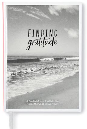 The cover of "FINDING GRATITUDE," a product by Compendium, showcases a black and white photograph of ocean waves softly caressing a sandy beach. The subtitle, "A Guided Journal to Help You Notice the Good in Every Day," makes it ideal for personal growth and self-reflection.