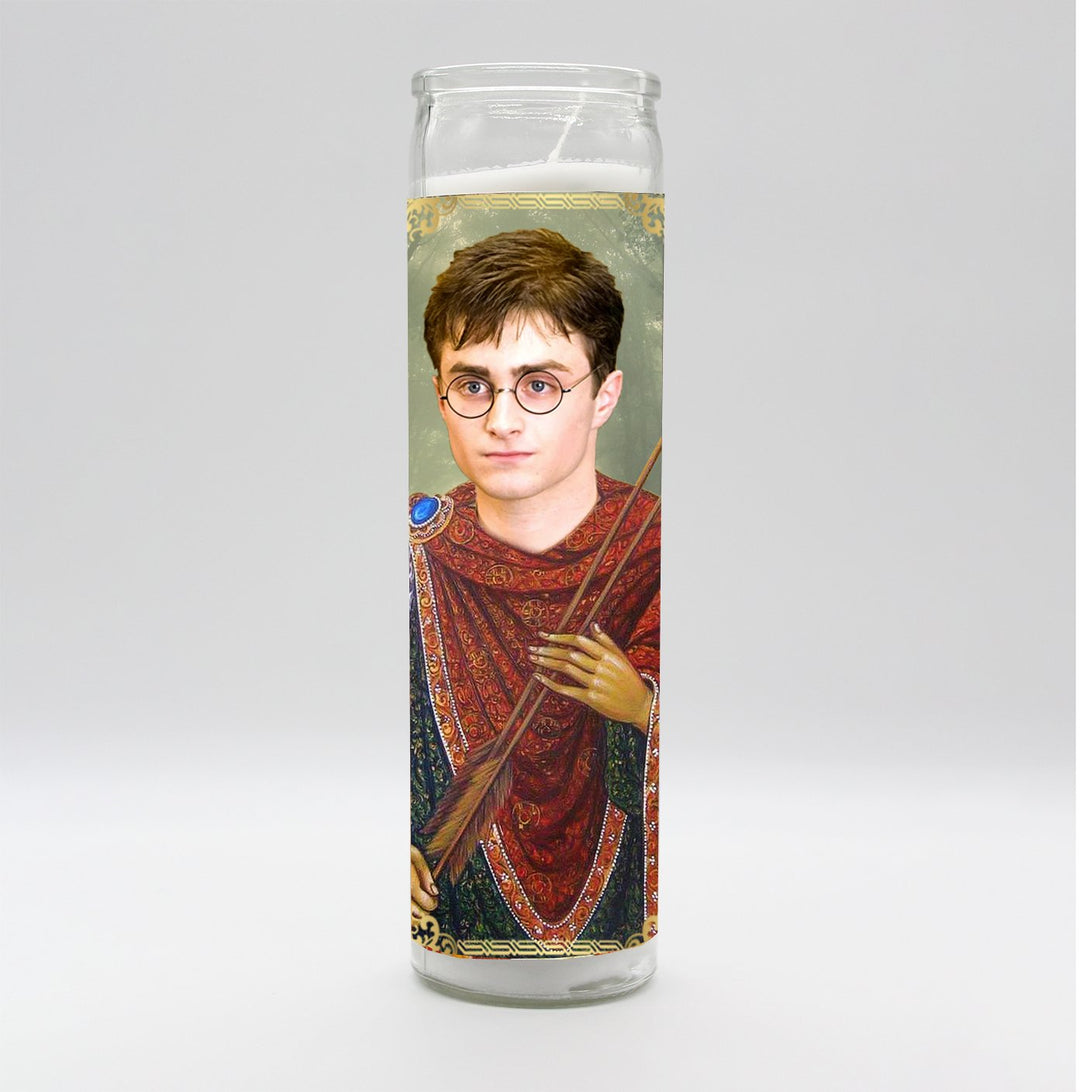 The BOBBYK BOUTIQUE Harry Potter Candle depicts a young man with glasses in a red robe holding a broomstick, resembling a saintly icon. It's unscented, tall, and features a plain light gray background, reminiscent of a celebrity shrine.