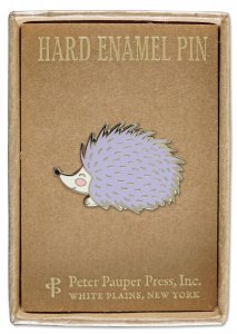 The Hedgehog Pin by PeterPauperP showcases a lavender-colored hedgehog with a cheerful expression, displayed on a brown cardboard backing. The top of the backing reads "Hard Enamel Pin," while the bottom states "Peter Pauper Press, Inc., White Plains, New York." This pin is ideal for gifting or adding to your collection.