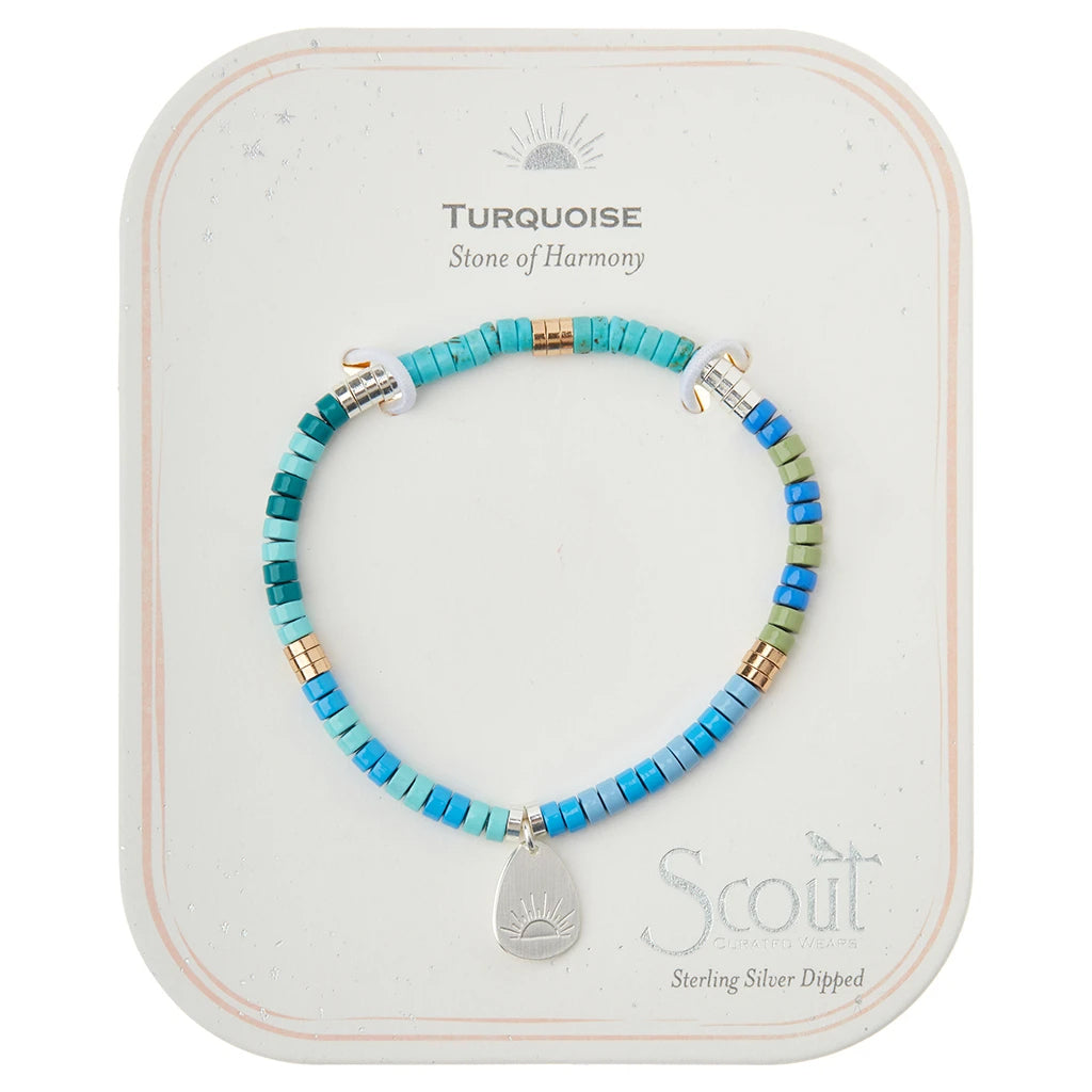 A turquoise beaded bracelet, featuring semi-precious stones and a 14K gold-dipped sun charm, is displayed on a card labeled "Turquoise - Stone of Harmony." The card includes the brand name "Scout Jewelry" and highlights the jewelry's positive properties. The beads are in shades of blue and green.
