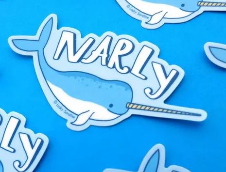 The Narly Narwhal Sticker from Lucky Sardine is a weatherproof, scratch-resistant vinyl sticker showcasing a blue and white cartoon narwhal with a long tusk. Above the narwhal, the text reads "NARLY." The bright blue background enhances the playful design, and multiple stickers of this same style are scattered around.