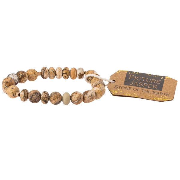 The Picture Jasper Stone Stacking Bracelet by Scout Jewelry showcases semi-precious gemstone beads of picture jasper in elegant shades of brown and beige, each bead offering unique textures and patterns. It comes with a brown tag that reads "Picture Jasper" and "Stone of the Earth" in white text.