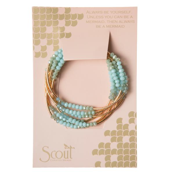 The Scout Jewelry "Wrap Turq Combo/Gold - Always Be Yourself Mermaid" bracelet set is beautifully displayed on a card with a mermaid scale design. The card features the text, "Always be yourself. Unless you can be a mermaid, then always be a mermaid." This set is perfect for ocean lovers who appreciate the enchanting allure of the Scout Wrap.